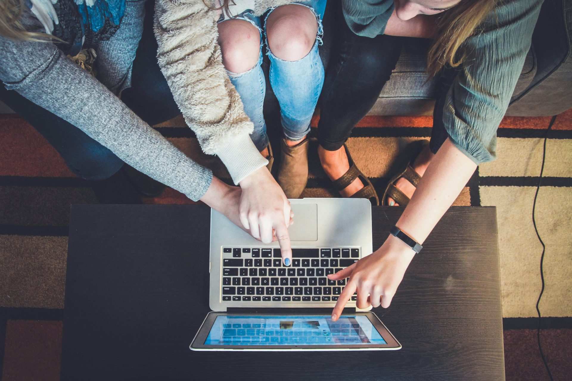 Three people pointing at laptop collaboratively