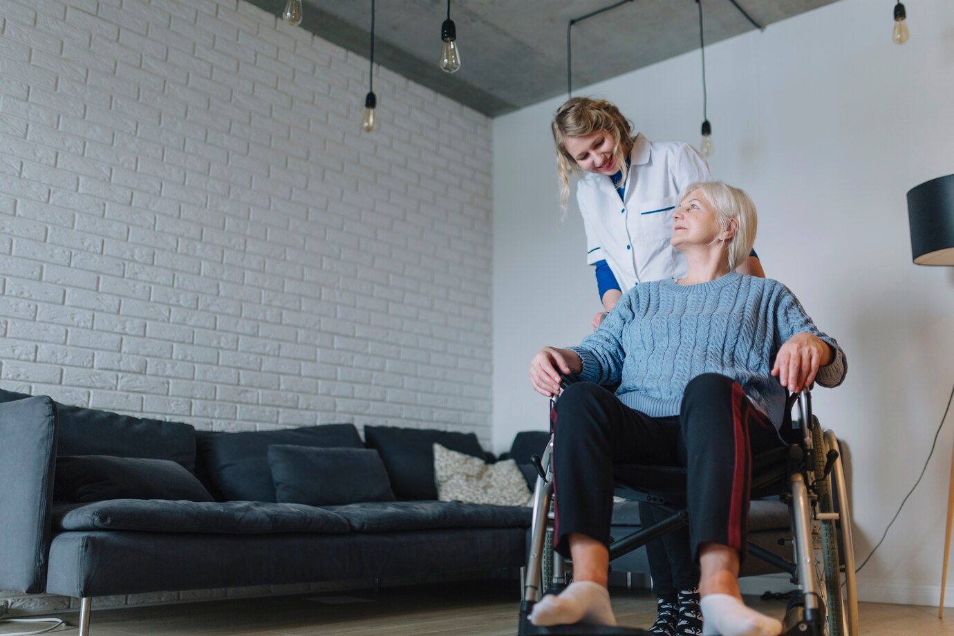 Nurse assisting elderly woman in wheelchair at home.