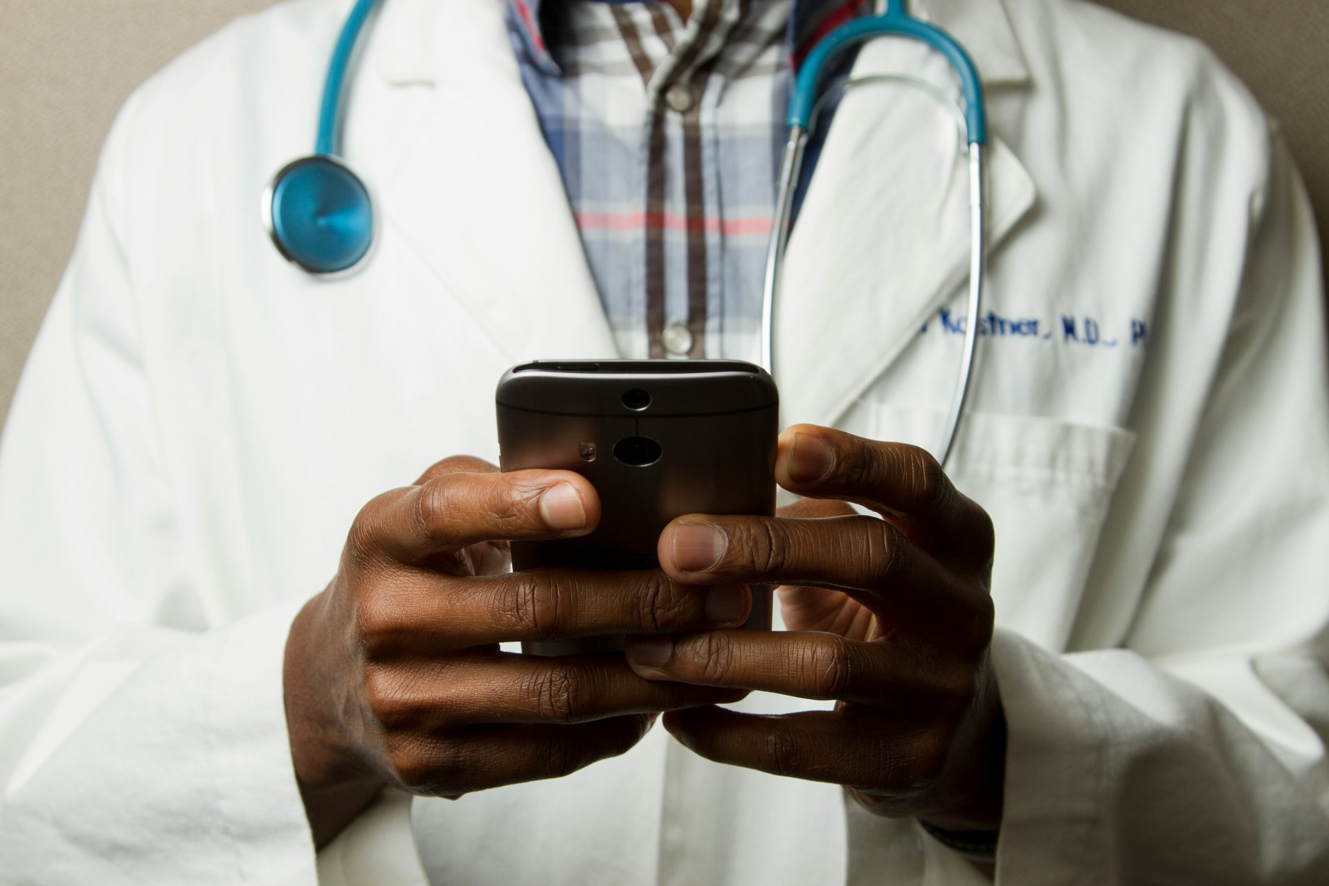 Doctor using smartphone, stethoscope around neck